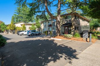 a building with a parking lot and a tree in front of it